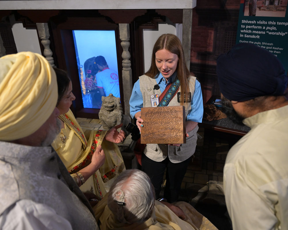 Museum staff member showing an object to a family.